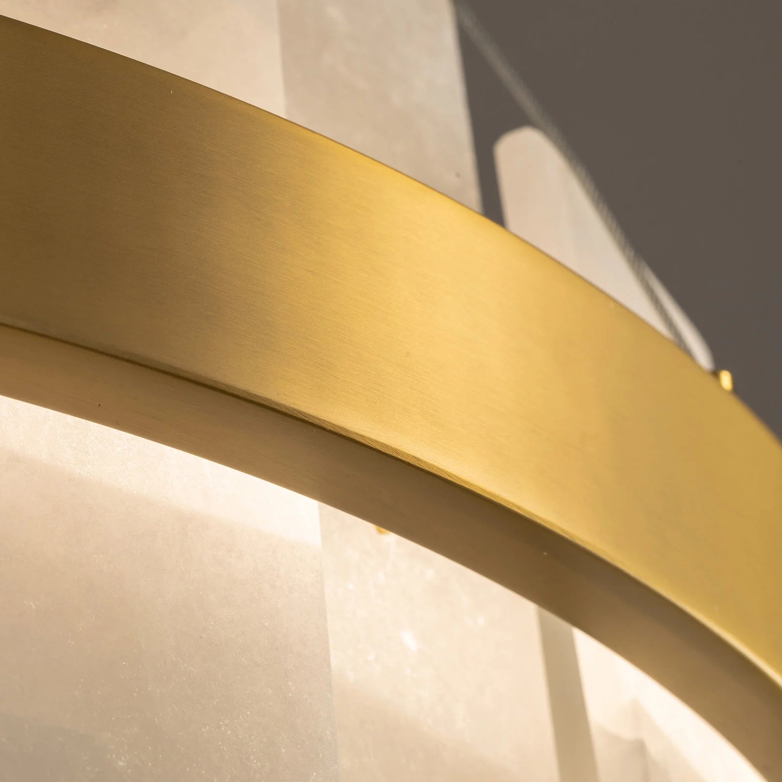 close-up-of-modern-round-alabaster-gold-chandelier-with-circular-gold-frame-and-evenly-spaced-alabaster-panels-emitting-warm-light-Feyran-lighting